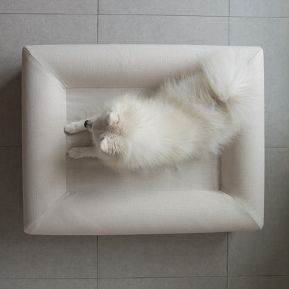 A white dog lying in the KINNE Bed, seen from above
